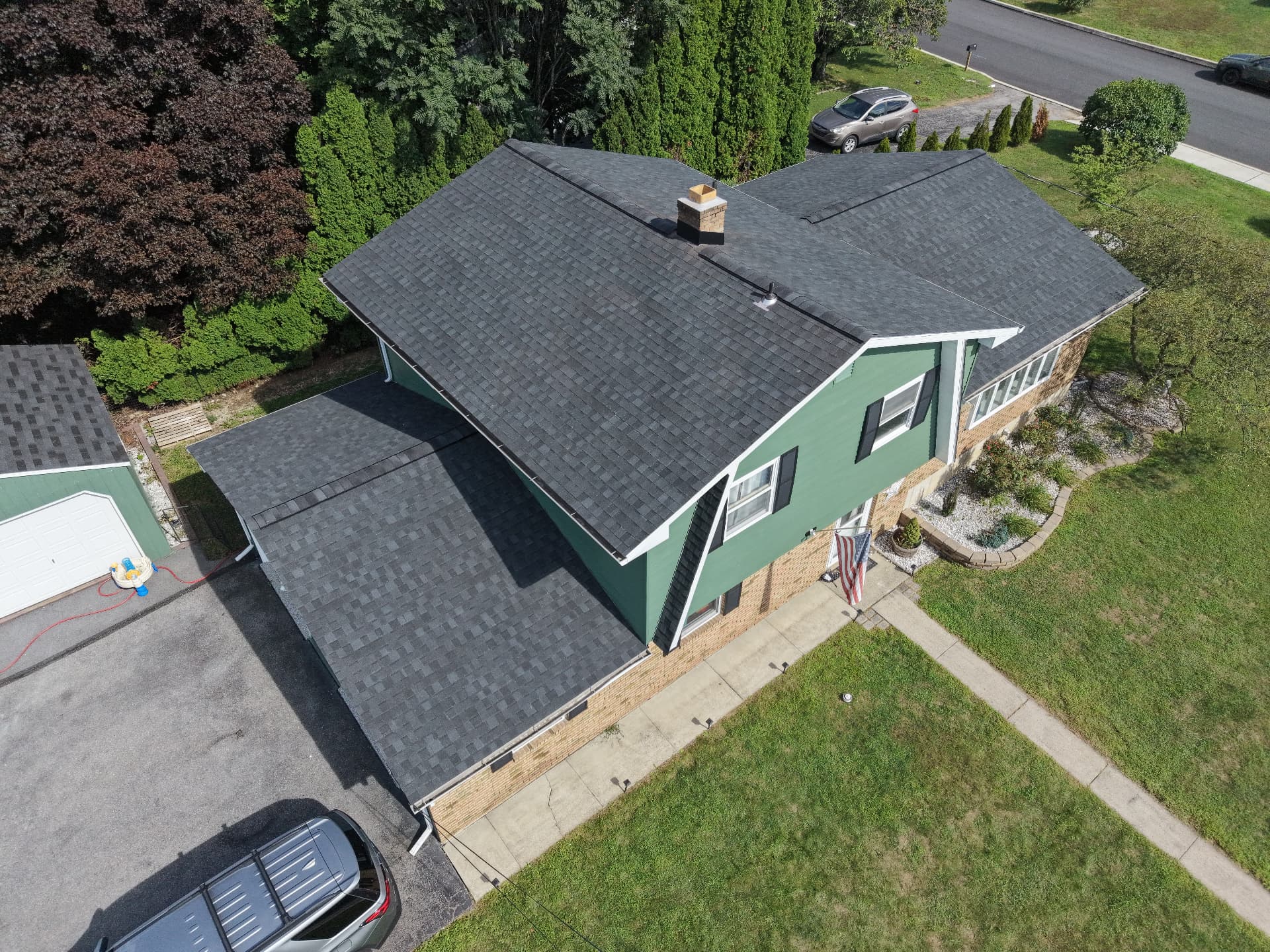 Aerial view of a green-sided home with a new dark shingle roof